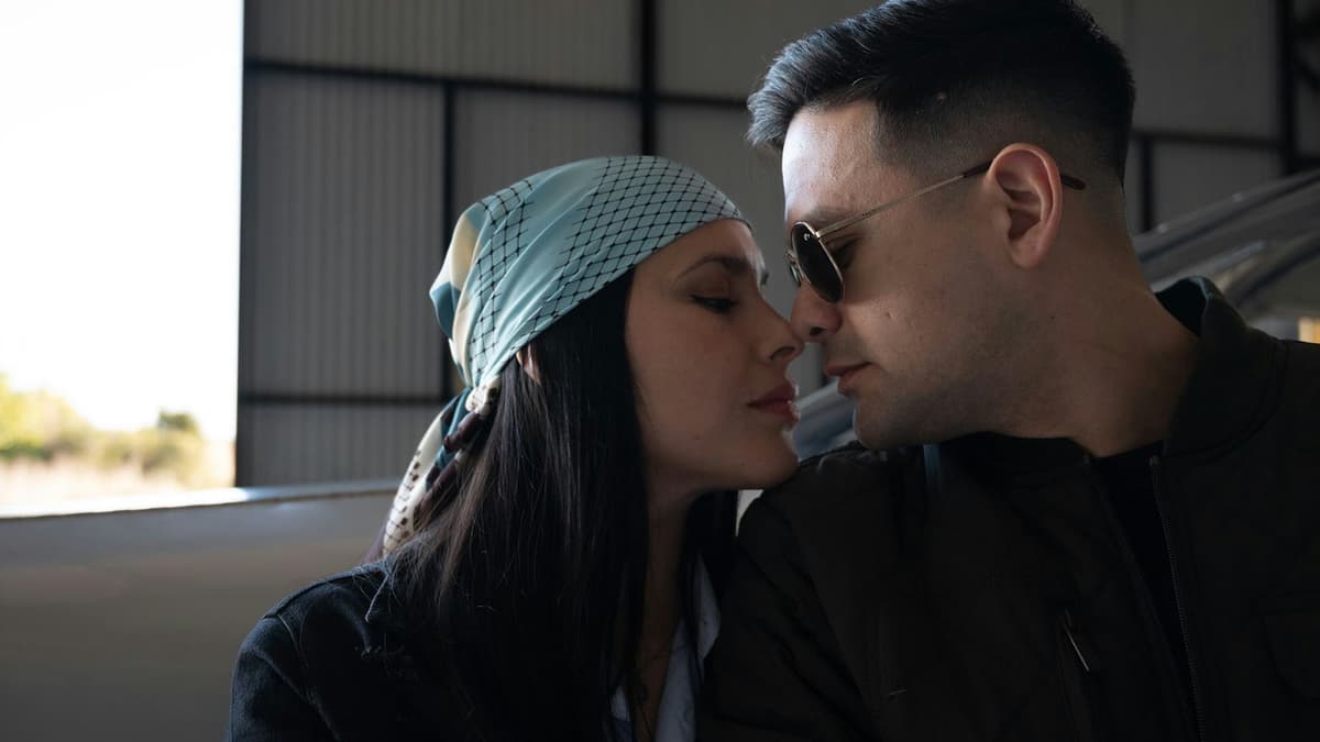 Romantic pose of couple in sunglasses and scarf inside a hangar.