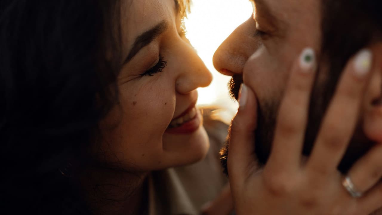 A close-up shot of a happy couple sharing an intimate moment at sunset, showcasing romance and connection.