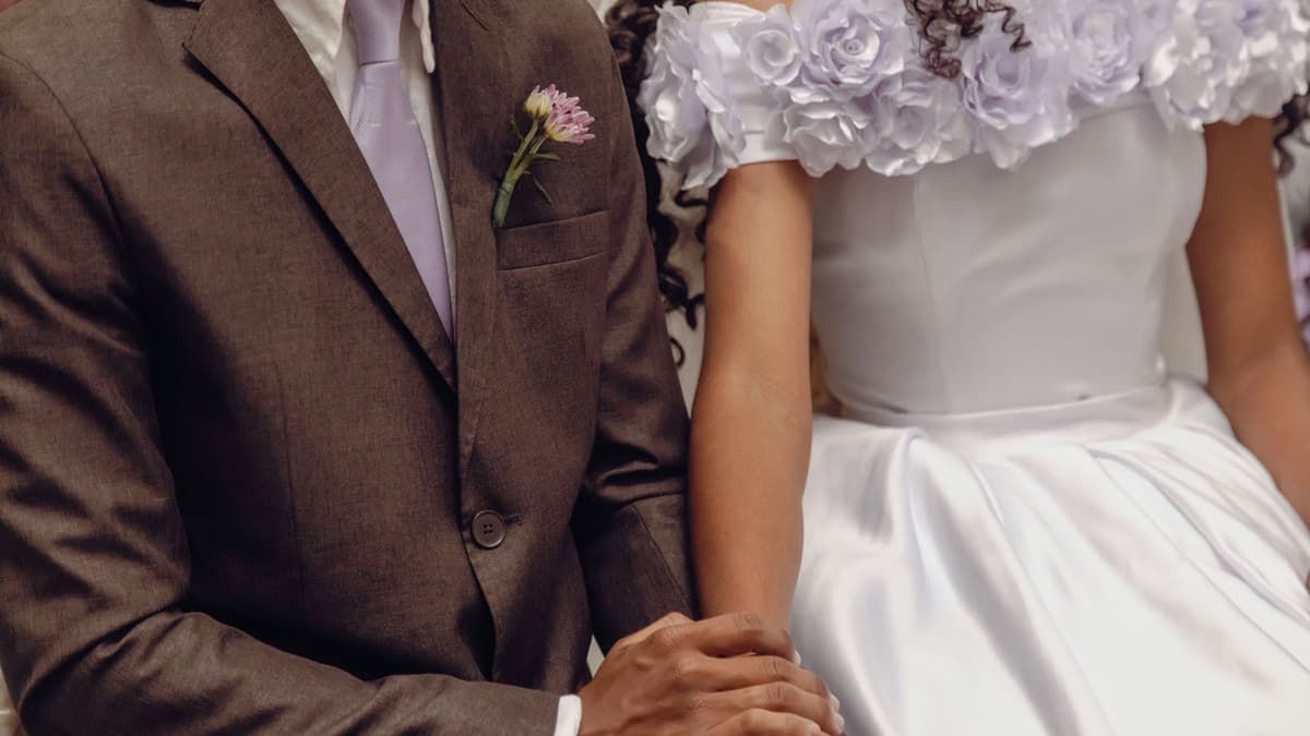 Close-up of a bride and groom holding hands, symbolizing unity and love at a wedding ceremony.