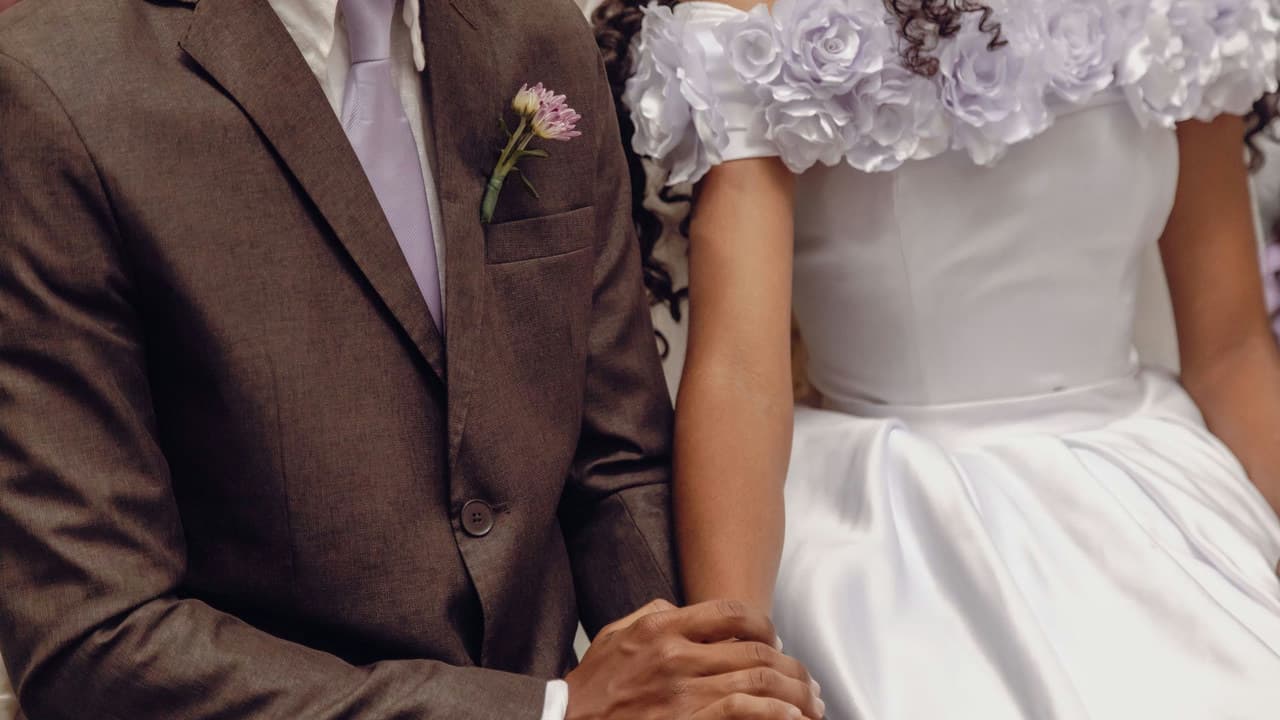 Close-up of a bride and groom holding hands, symbolizing unity and love at a wedding ceremony.