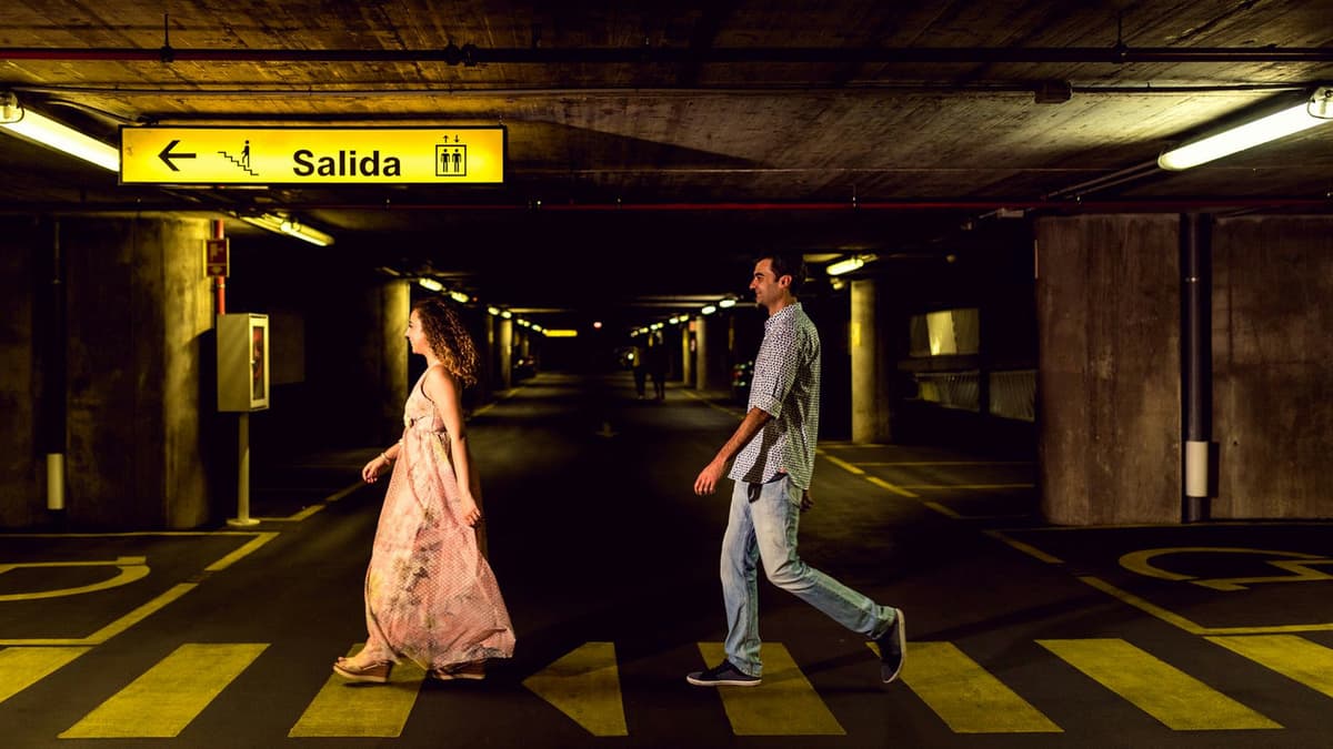 A couple strolling in a dimly lit underground parking garage in Toledo, Spain.