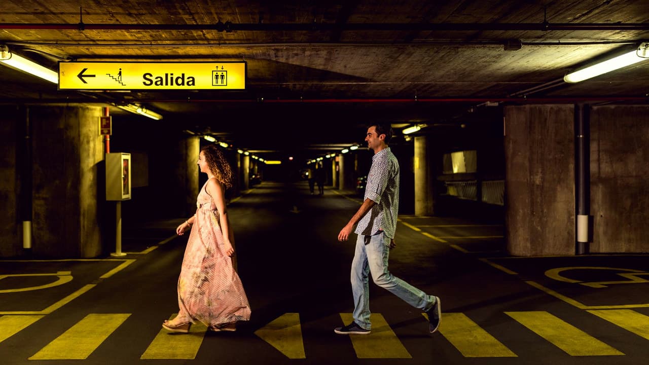 A couple strolling in a dimly lit underground parking garage in Toledo, Spain.