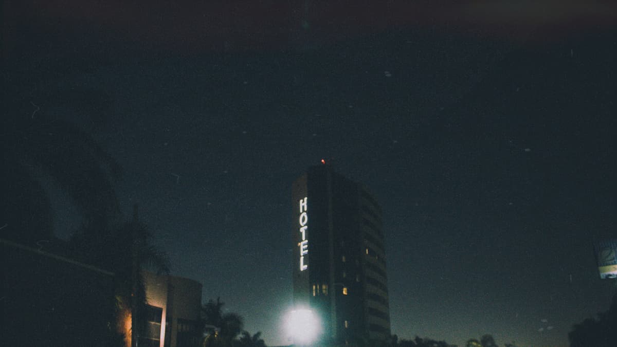 Low angle shot of a hotel with neon signage at night, creating a moody urban atmosphere.