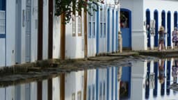 Charming colonial architecture reflects in flooded streets of Paraty, Brazil, capturing serene urban beauty.