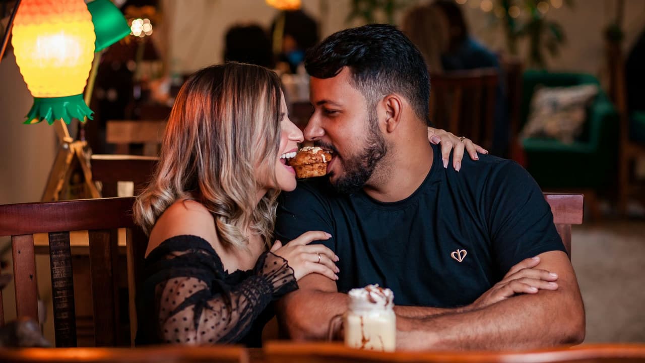 A joyful couple shares a dessert in a cozy cafe setting, highlighting togetherness and romance.