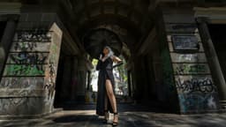 Elegant woman with black umbrella in a graffiti-adorned archway, Mexico City.