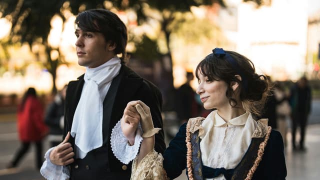 A couple dressed in vintage outfits walking outside in urban setting.