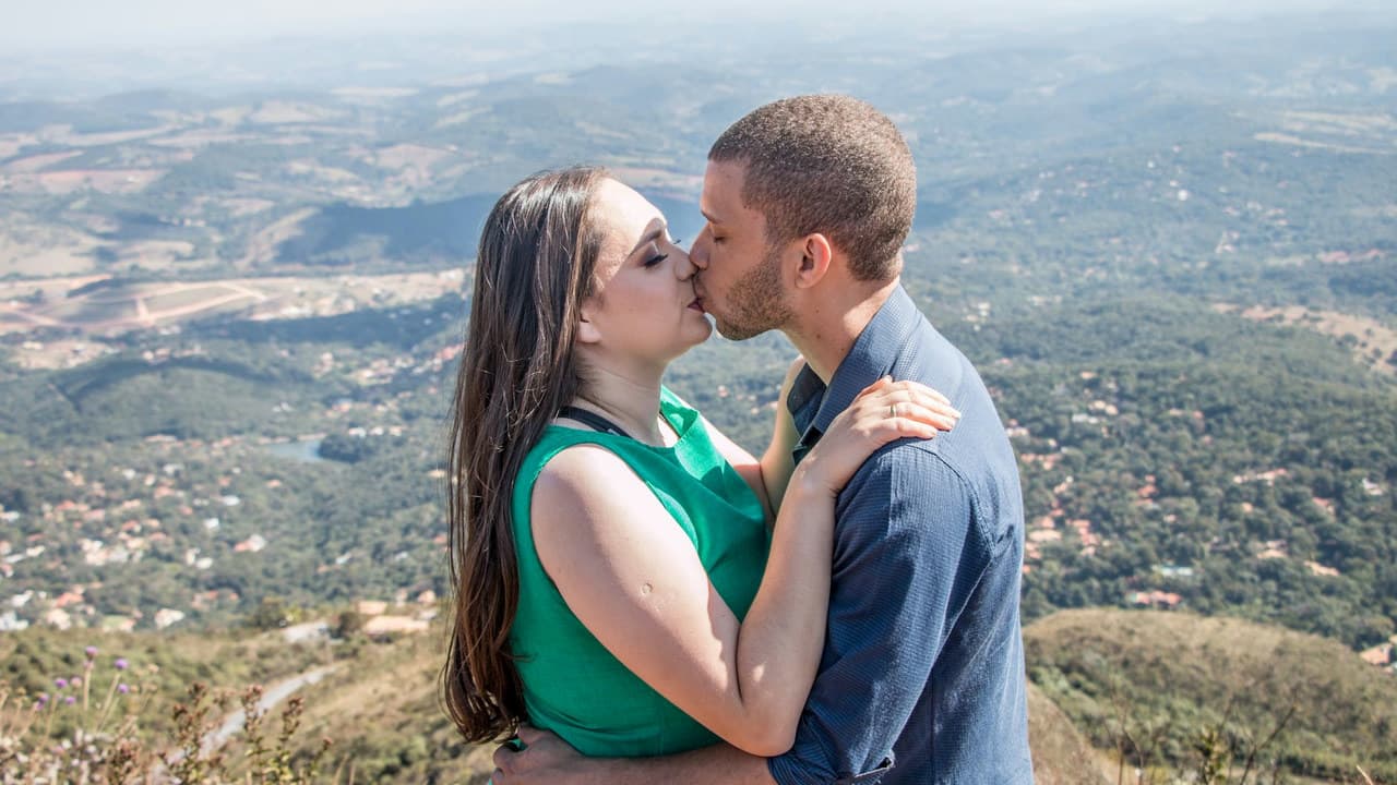 A couple shares a romantic kiss with a breathtaking view of Belo Horizonte's mountainous landscape.